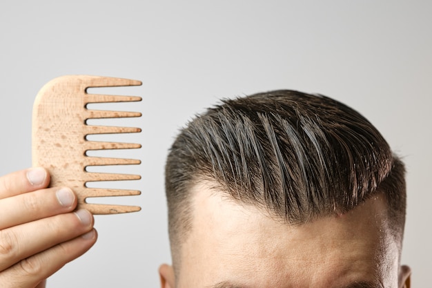 Man brushing his hair with a wooden comb