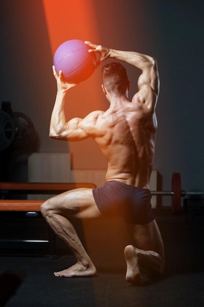 Man buigen spieren in sportschool met medicijnbal