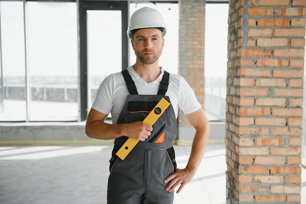 Man builder working in construction site male repairer in\
overall and helmet