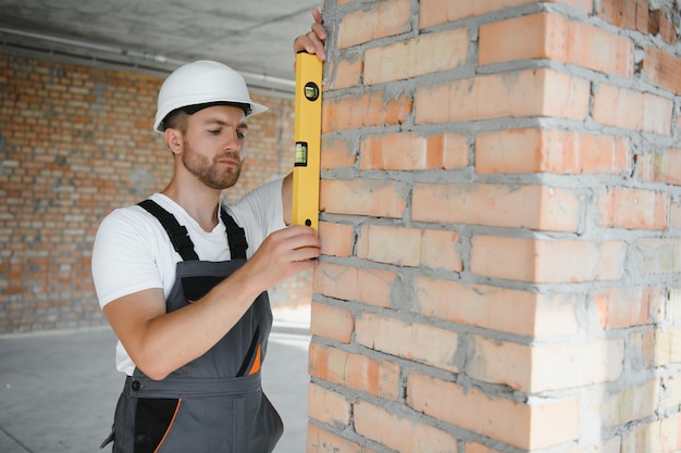 Man builder working in construction site male repairer in\
overall and helmet