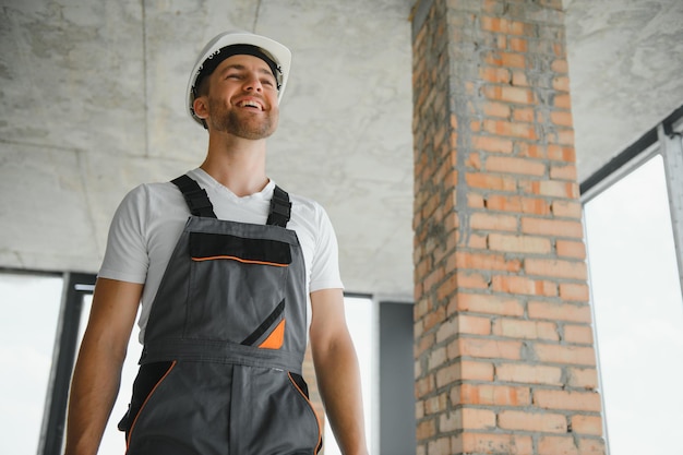 Man builder working in construction site male repairer in\
overall and helmet