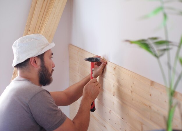家を建て、ハンマーと木を使って働く男性