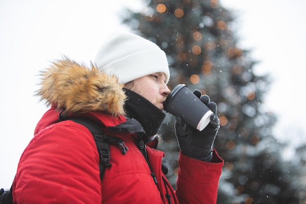 Man buiten koffie drinken uit papieren beker wintertijd opwarmen