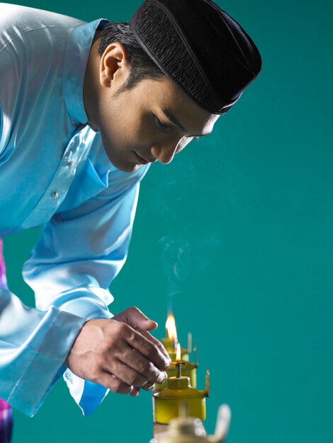 Man burning oil lamps against green background