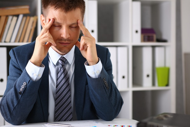 A man in business attire is trying to concentrate