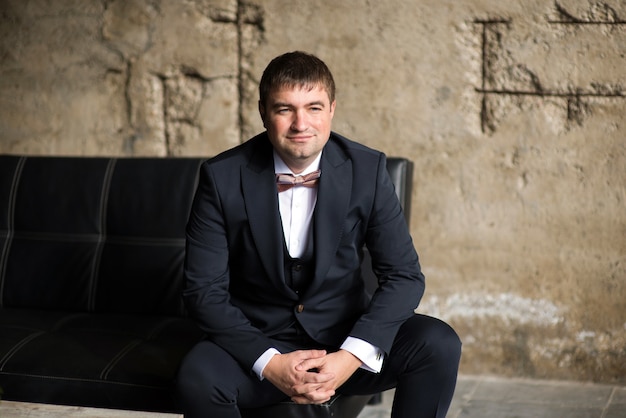 Man in business suit and bow tie on the sofa