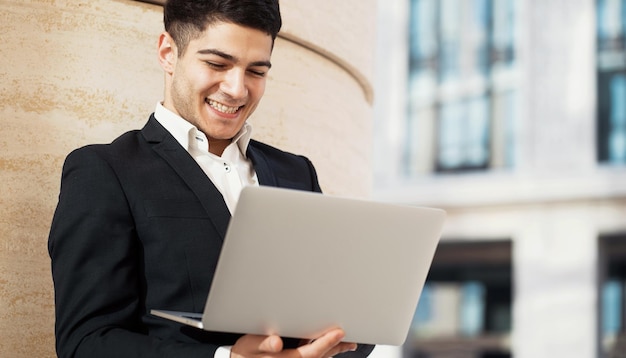 A man in a business suit is working on a laptop typing a message to a partner Darkhaired