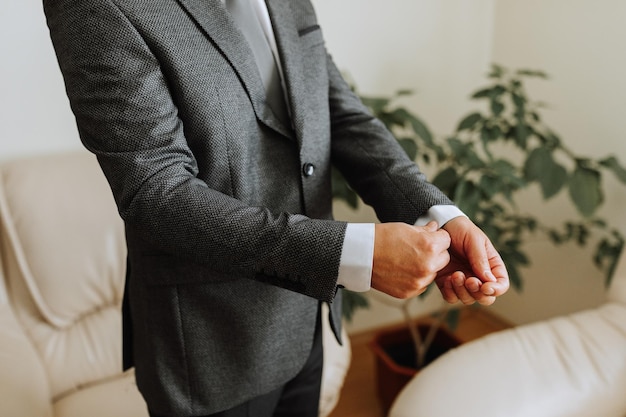 A man in a business suit puts on and adjusts a sleeve with a clip The concept of wedding day fashion business mens style