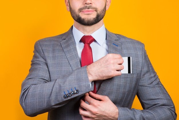 A man in a business suit puts a bank card in a kaman close-up on a yellow