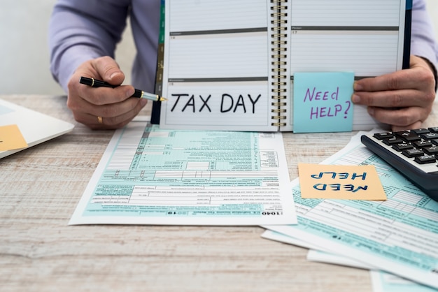 A man in a business suit writes a 1040 tax form in the office. Male hands fill on paper with calculator at workplace. Accounting concept