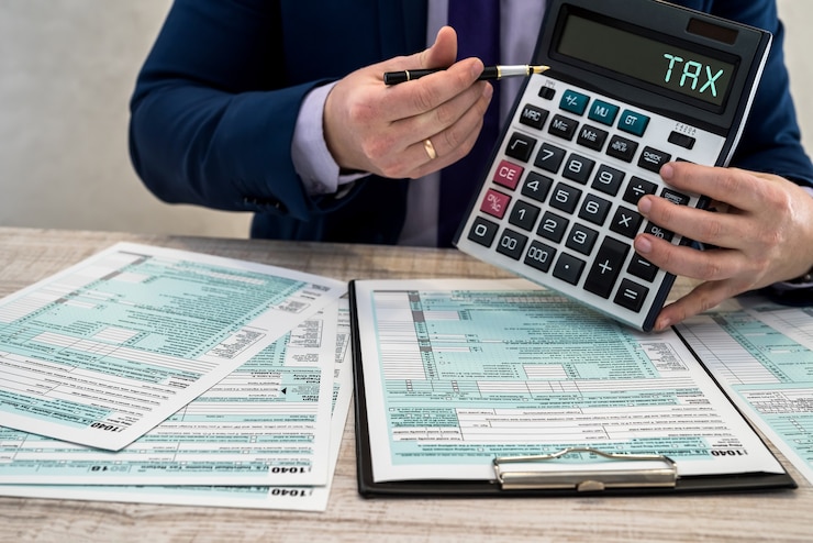 A man in a business suit writes a 1040 tax form in the office. Male hands fill on paper with calculator at workplace. Accounting concept