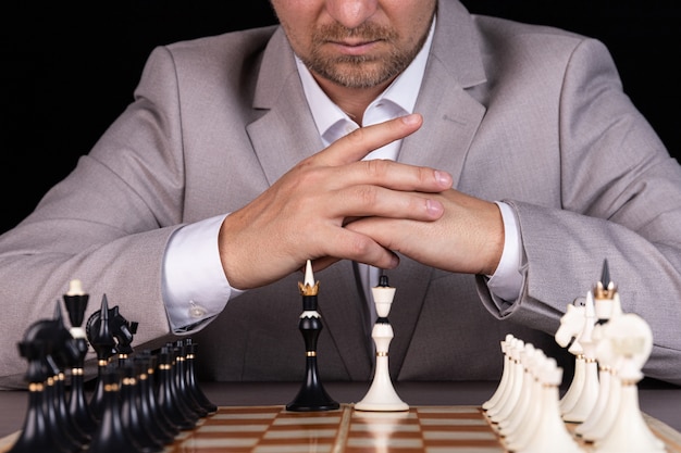 A man, a businessman, is sitting at a chessboard