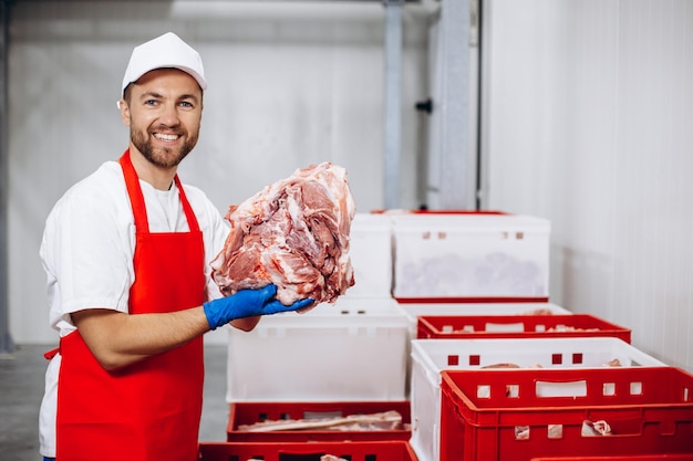 Man butcher at the freezer puts meat into container