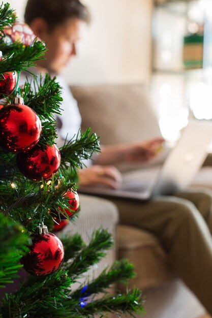 Человек покупает рождественские новогодние подарки онлайн с помощью телефона, ноутбука