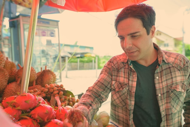 Foto uomo che compra frutta alla bancarella del mercato