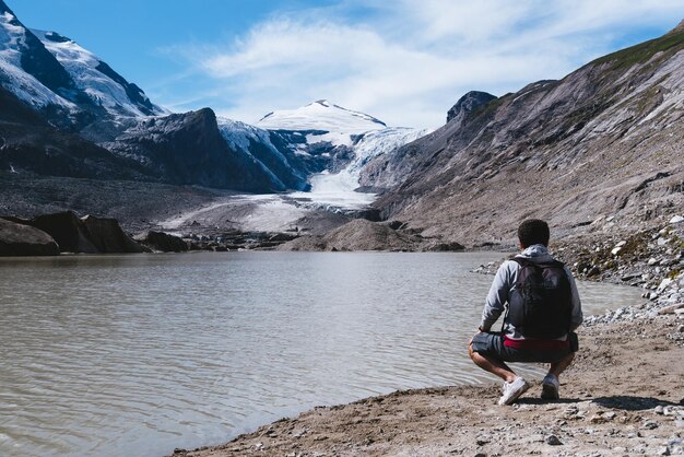 Man by lake looking at alpine glacier