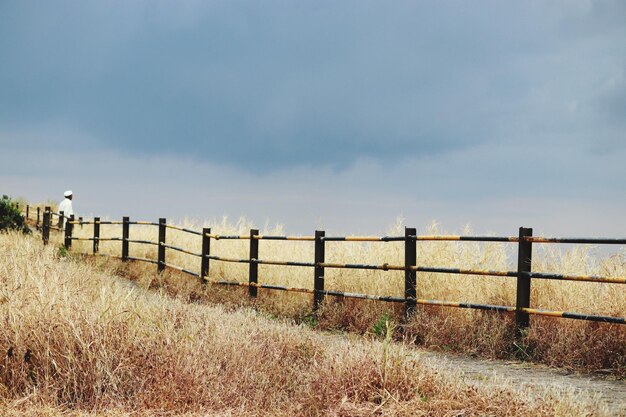 Photo man by railing on field against sky