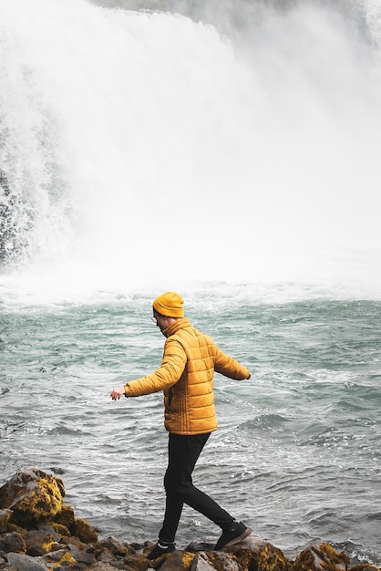 Человек у водопада идет по скалам