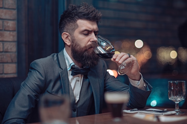 Man in cafe drinking alcohol bearded man rest in restaurant with wine glass perfect wine alone hipster awaiting in pub businessman with long beard drink in club