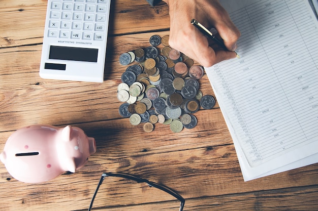 Man calculates money Piggy bank and business documents on desk