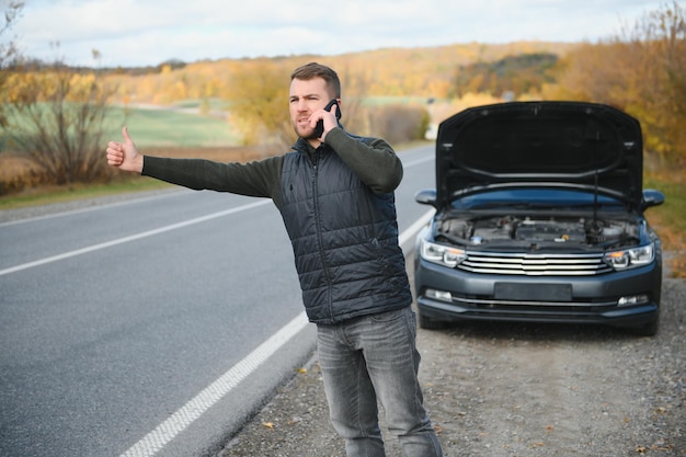A man calls a phone number to talk to a mechanic The car broke down on the roadside The concept for fix help problem repair blurred background