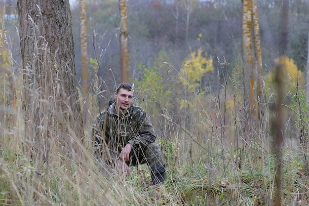 Мужчина в камуфляже и с ружьями в лесополосе на весенней охоте