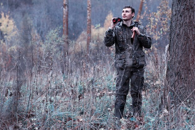 Man in camouflage and with a hunting rifle in a forest on a spring hunt