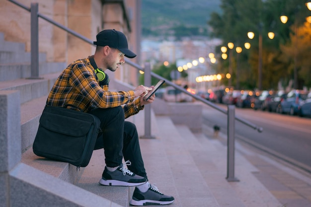 Man in a cap works remotely with a tablet at night