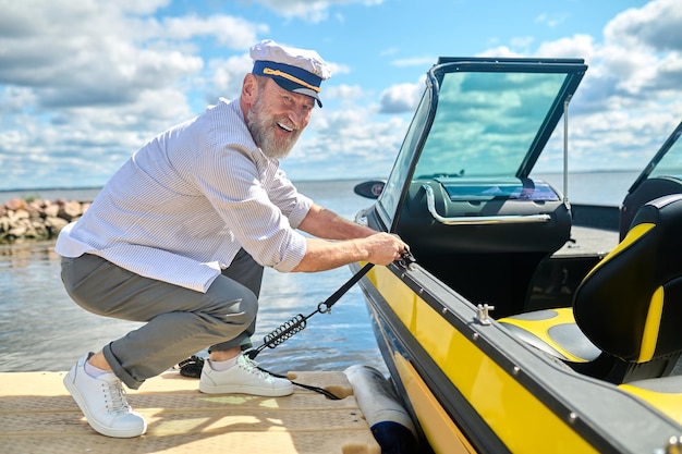 A man in a captains cap getting the boat ready