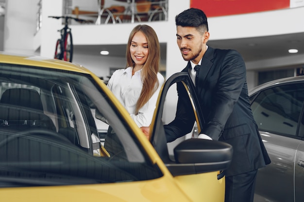 Man car dealer showing a woman buyer a new car in car salon