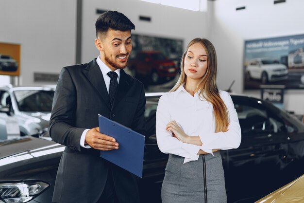 Man car dealer showing a woman buyer a new car