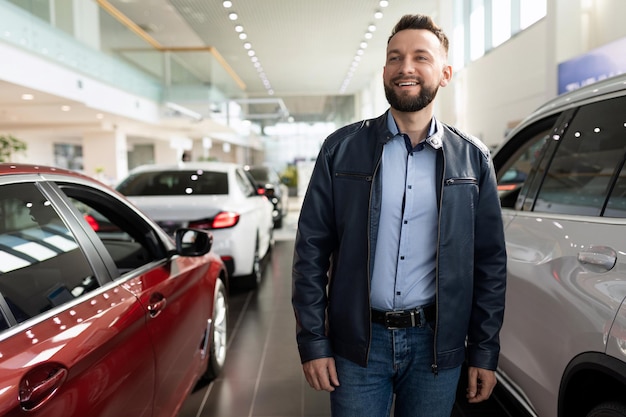 A man in a car dealership chooses a new car considering options