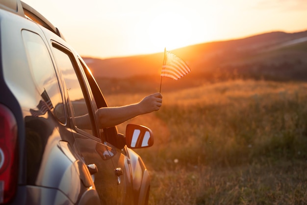 Man in the car holding a waving american USA flag