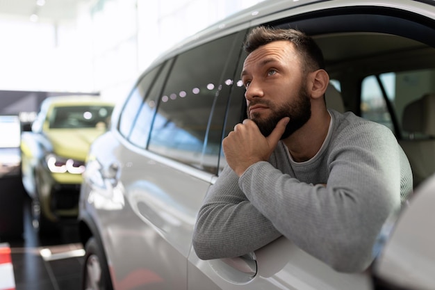 A man in a car showroom thinks about buying a new car