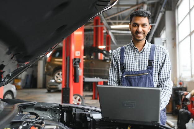 Man car technician mechanic repairing car problem of engine during system checking detail using tablet computer for maintenance and fixing in car garage