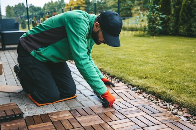 Photo a man carefully installing wooden floorboards on the terrace at home