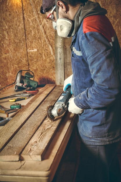 男大工は自宅の工房で研削盤で木片を粉砕します
