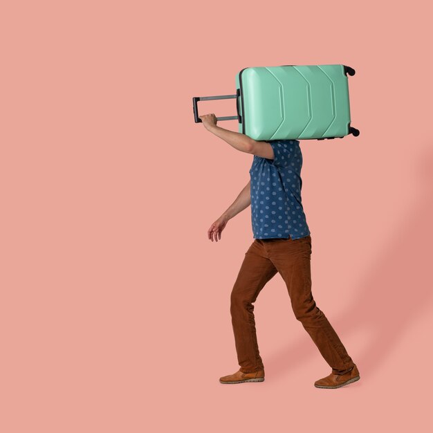 写真 男はピンクに行く彼の肩にプラスチックのスーツケースの荷物を運ぶ