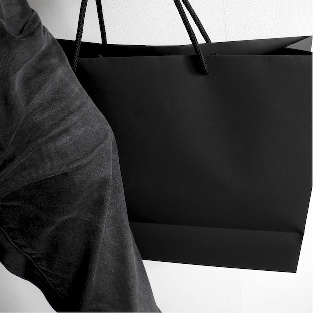 A man carries a black craft paper shopping bag
