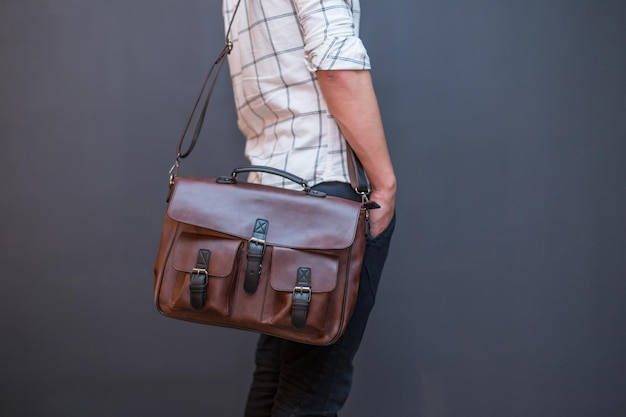 Man carries brown leather messenger bag in the hand