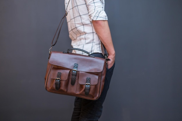 Photo man carries brown leather messenger bag in the hand