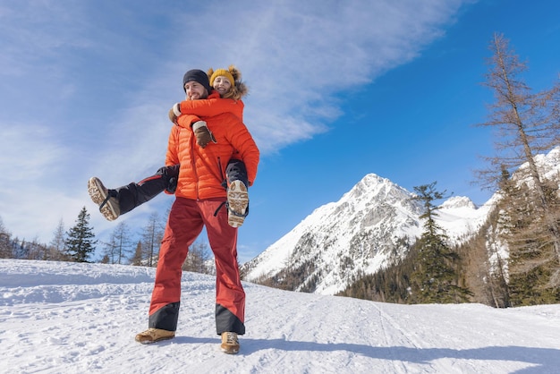 Man carries his girlfriend on his back in snowy mountain area