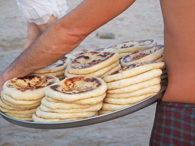 Un uomo porta un vassoio con khachapuri caldo. venditore di cibo sulla spiaggia.