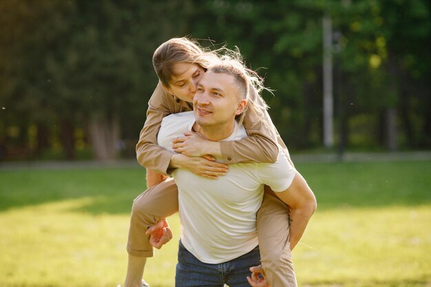 Man carry his wife piggyback in a spring park and woman kissing him