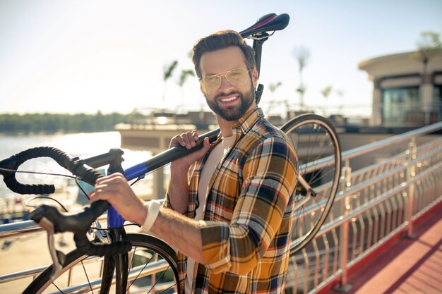 彼の肩に自転車を運ぶ男