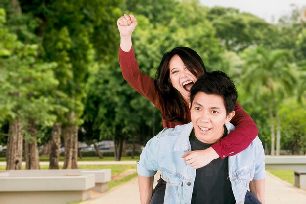 Man carrying friend against trees