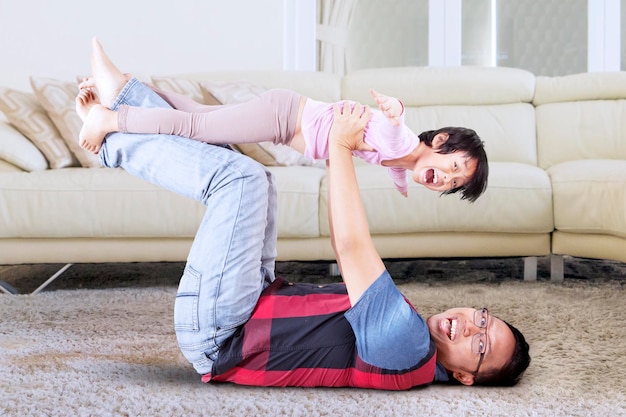 Man carrying his daughter joyfully in living room