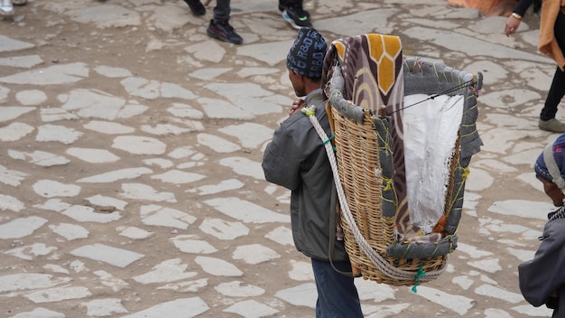 a man carrying a jute bucket on her shoulders 01 SEP 2023 Shri Kedarnath Temple dedicated to Lord Shiva Rudraprayag district of Uttarakhand India