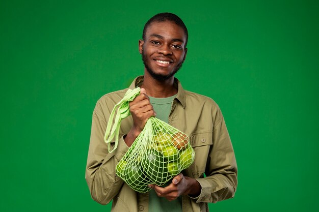 Photo man carrying mesh bag with green fruit