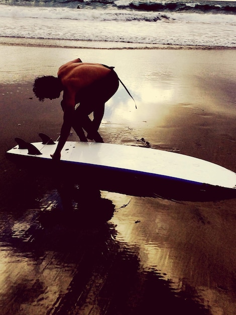 Photo man carrying surfboard on beach